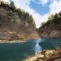 Colour image of rocky cliffs on both sides of calm river