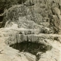 Black and white photograph of rock ledge with large, round hole